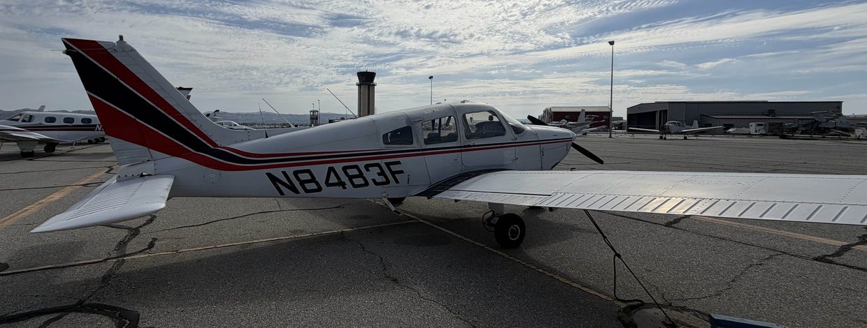 N8483F, a 1976 Piper Archer II in red and navy trim, on the ramp at Chino Airport